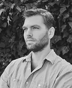Johnson in a gray sweater and crossing his arms.