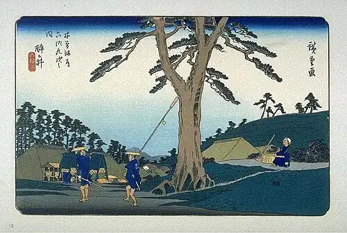 Woodblock print showing travelers beneath a pine tree with thatched buildings and distant mountains