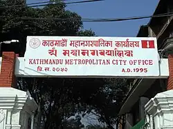 Signboard of Kathmandu Metropolitan City Office in Ranjana script (second row).