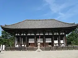 Wooden building with white walls and a trapezoidal roof.