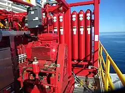 Red hydraulic accumulator and pump assembly used to supply pressurized fluid in a fluid power system on an offshore platform
