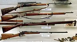 Display of rifles, with a civilian Krag–Jørgensen M1894 featuring a carved stock on top.