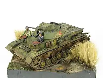 A diorama of a Kugelblitz Self-Propelled Anti Aircraft Gun sitting in a field with dried grass on its sides