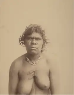 Portrait photograph of a shirtless Aboriginal woman wearing a necklace