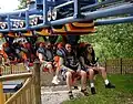 A Vekoma Suspended Looping Coaster train seats riders 2 across