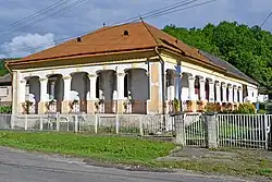 A traditional dwelling-house in Lénárddaróc with an orange roof and wraparound arches.