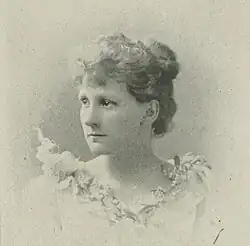 19th-century B&W portrait photo of a woman with her hair in an up-do, wearing a dark, fitted blouse.