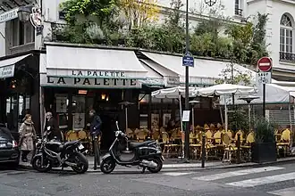 Parisian café with yellow chairs and green awnings on a street corner