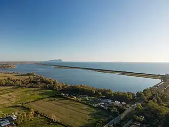 A body of water with greenery and houses to one side and of the body of water to the other side.