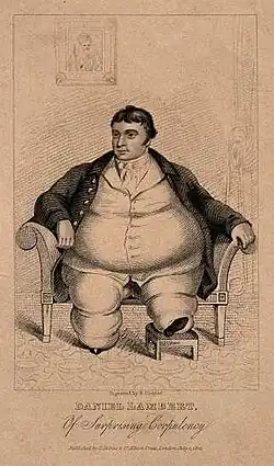 Smartly dressed fat man with dark hair sitting on a chair