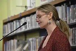 This image shows Irish poet, Leanne O'Sullivan, standing at a microphone in Cork City Library.