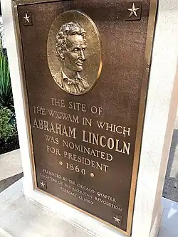 A plaque dedicated by the Daughters of the American Revolution, marking the spot of the Wigwam. First unveiled in 1909, it was found in storage and rededicated in 2017. The reverse side is a plaque that marks the spot of the Sauganash Hotel.