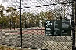 Fence around a park recreation area, with a view of the park area inside the fence.