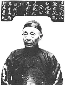 Black and white portrait photograph of Liu Xinyuan. He has a wrinkled face, and wears a dark top and cap with no visible hair.