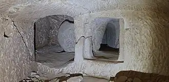 Subterranean hiding complex at Horvat 'Eton, showing rock-cut entrances, a sealing stone, and chambers