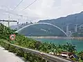 Bridge under construction (summer 2023). Cantilevered pylons and an overhead cable crane are visible
