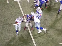 A Dallas Cowboys offensive lineman holds Justin Tuck, preventing him from tackling Marion Barber.