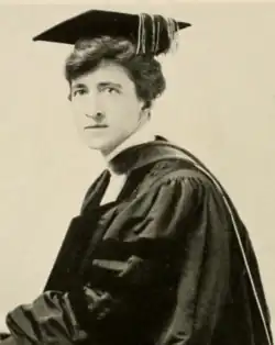 A white woman, wearing academic cap and gown