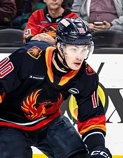 Hockey player wearing a dark blue and orange Coachella Valley Firebirds jersey