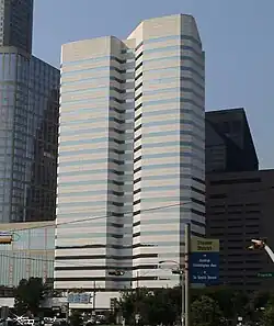 Two attached concrete and glass office towers, one with an irregular shape. Both have uniform horizontal bands of windows alternating with the concrete.
