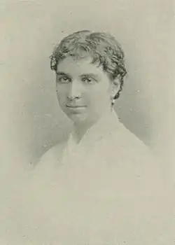 B&W portrait photo of a young woman wearing a pale, high-collared blouse with her hair in an up-do.