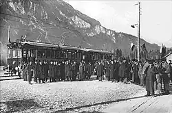 Black and white photograph of an electric multiple unit train in the snow with a crowd in front of it posing for the camera.