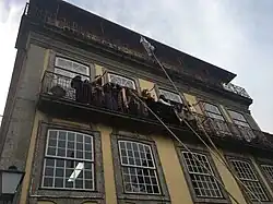 Young women on a balcony, above three long spears