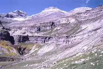 A landscape photo of a large mountain with multiple cliff faces, small feature seen on the right side