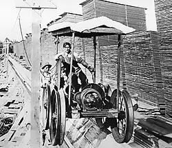 An electric-powered flume cart raises boards to the tops of the drying piles.: 101