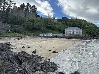 Image of a beach with a small building and forest in the background