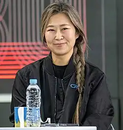 Maggie Kang directly facing the camera while seated at a table