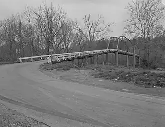 A monochromatic image of a truss bridge held up by stone pillars