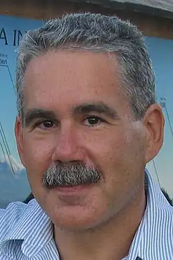 A middle-aged man with a moustache smiling slightly