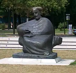 Gray statue in park of Bearded man in a robe, sitting