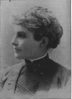 19th-century B&W portrait photo of a woman with her hair in an up-do, wearing a dark, fitted blouse.