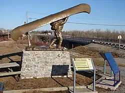 Voyageur statue in Mattice, with bridge over the Missinaibi River in the background