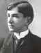 A black-and-white photograph of a young man in a suit with a tie