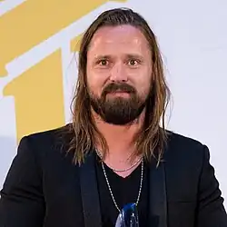 An image of a man with long hair looking slightly off-camera.