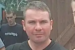 Head and shoulders of a man with greying hair.