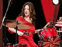 Meg White during a performance, sitting at a red drum kit with peppermint decals