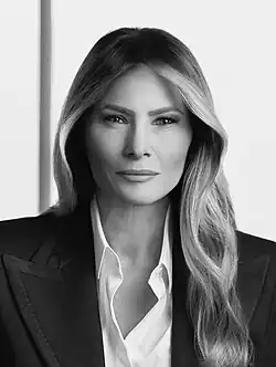 Black-and-white portrait of Melania Trump, a middle-aged white woman with long dark hair, wearing a black suit.