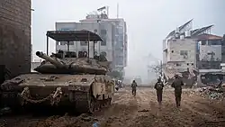 Israeli Merkava Barak with KAZ Meil Ruach and an anti-drone grille, in an urban environment during daytime