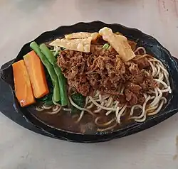Mie ayam hotplate, cooked and served on a hot cast iron