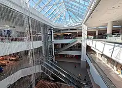 A three-storey shopping centre atrium covered by a large glass skylight