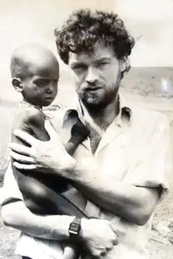 Photograph of Michael Elmore-Meegan holding a child, pictured to his left.