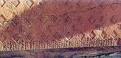 6th century BCE inscription with the Phrygian alphabet from the Midas Tomb, Midas City: ΒΑΒΑ: ΜΕΜΕϜΑΙΣ: ΠΡΟΙΤΑϜΟΣ: ΚΦΙJΑΝΑϜΕJΟΣ: ΣΙΚΕΝΕΜΑΝ: ΕΔΑΕΣ (Baba, memevais, proitavos kziyanaveyos sikeneman edaes; Baba, advisor, leader from Tyana, dedicated this niche).[38][39]