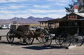 Two wagons in front of a wooden building with a surrounding patio.