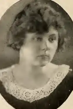 A young white woman, wearing a dark dress with a white lace collar