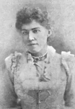 A young white woman with dark hair, wearing a light-colored gown