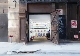 Two large metal doors open to a white closet-sized museum with lots of colorful exhibits on the shelves